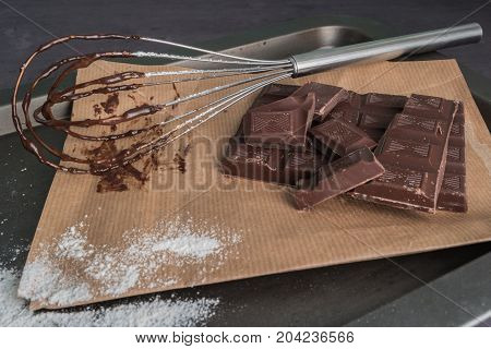 Chocolate chunks. Chocolate bar pieces and whisk on board.