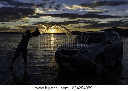 The man washed the luxury car with the blue sky threw the bucket into the side of the car.The car wash guy throws a bucket in the side of the car.