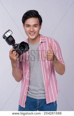 Young asian photographer holding digital camera while working in studio