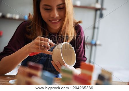 Young Asian woman enjoying pottery process in studio