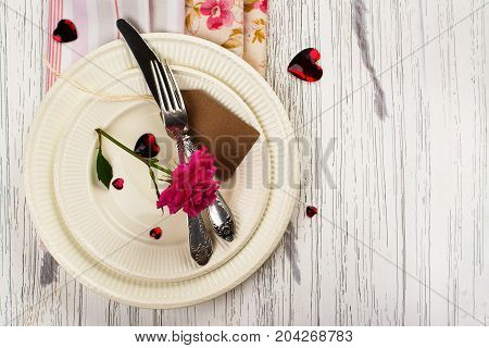 Valentines day table setting with white plates, hearts and rose. Space for text. Holidays background