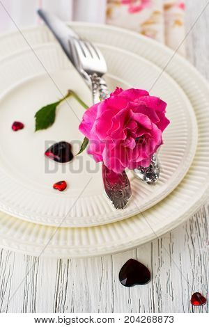 Valentines day table setting with white plates, hearts and rose. Space for text. Holidays background