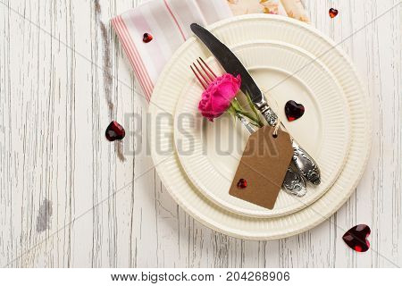 Valentines day table setting with white plates, hearts and rose. Space for text. Holidays background