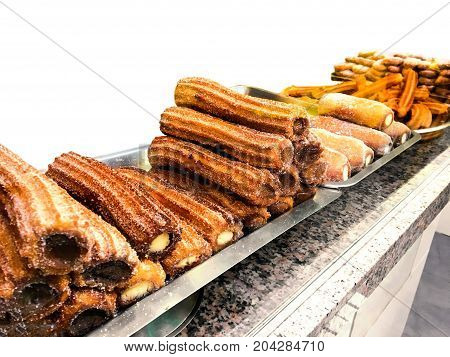 Churros on a market stall in a bakery shop. Sweet Famous Spanish dessert with chocolate sauce close up