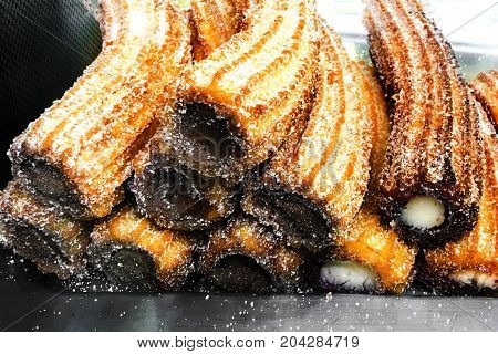 Churros on a market stall in a bakery shop. Sweet Famous Spanish dessert with chocolate sauce close up