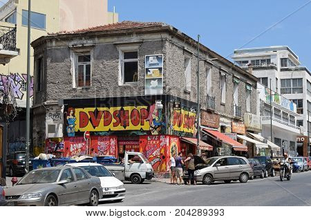 ATHENS GREECE - AUGUST 4 2016: Sex shop with pornographic movies on a rundown building and people in downtown Athens Greece.