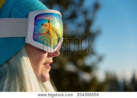 Close-up Profile Shot Of A Smiling Female Snowboarder Wearing Skiing Mask, Looking Away, Resting In