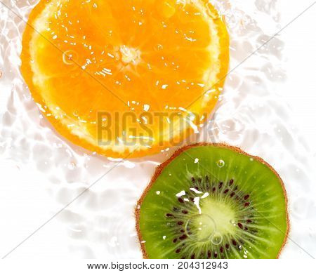 juicy kiwi and orange in water on a white background. macro