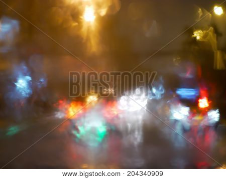 blurry traffic jam bokeh light view outside road from inside a car while raining night cityscape of abstract background
