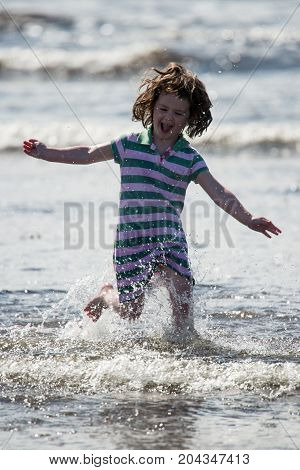 View of Young little girl on beach playing in the surf