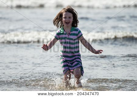 View of Young little girl on beach playing in the surf
