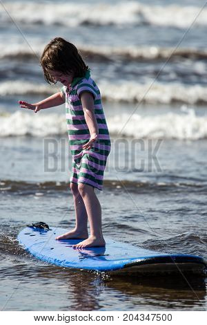 View of Young little girl on beach taking surfing lessons