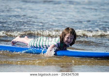 View of Young little girl on beach taking surfing lessons
