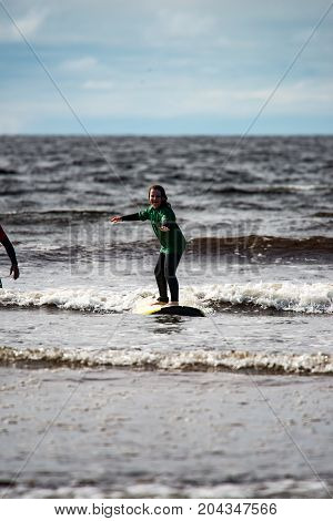 View of Young little girl on beach taking surfing lessons