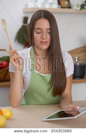 Young  woman is making online shopping by tablet computer and credit card. Housewife found new recipe for  cooking in a kitchen.