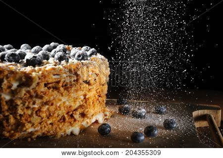 layered cake, Napalion cake, puff cake with blueberry sprinkled with powdered sugar, on a rough wooden backing, menu background