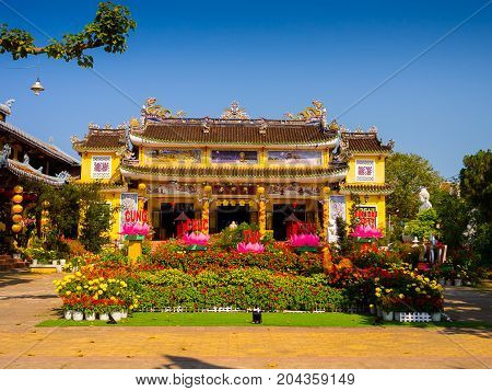 HOIAN, VIETNAM, SEPTEMBER, 04 2017: View of an ancient temple with a beautiful jarden with colorful flowers at hoian, in a sunny day in Vietnam.