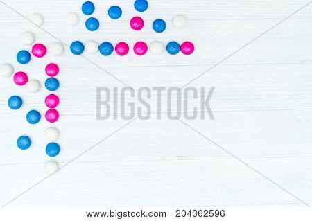 Part of the frame from colorful mint coated candies texture on white wooden background. Top view. Copy space