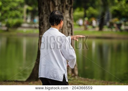 Man exercising by Tai Chi in a outdoor park for exercise healthy