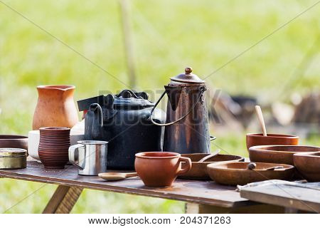 Wooden table with old fashioned wooden and earthenware crockery. Historical reconstruction of 19 century.