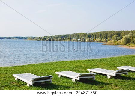 White wooden chaise lounges on the bank of the Ilyinsky reservoir. Outdoor recreation. Moscow region Russia.