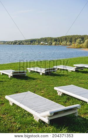 White wooden chaise lounges on the bank of the Ilyinsky reservoir. Outdoor recreation. Moscow region Russia.