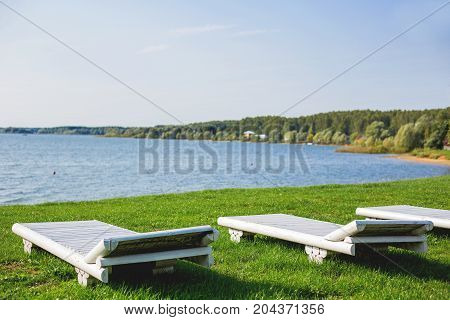White wooden chaise lounges on the bank of the Ilyinsky reservoir. Outdoor recreation. Moscow region Russia.