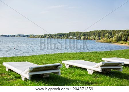 White wooden chaise lounges on the bank of the Ilyinsky reservoir. Outdoor recreation. Moscow region Russia.