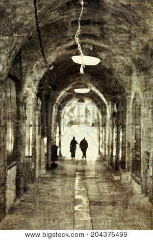 Muslim women are wearing religious hijab in the narrow alley of old city of Akko in Israel. Typical Street Scene among traditional stoned houses in old Acre. Vintage style toned picture