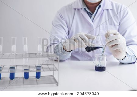 Scientist or medical in lab coat working in biotechnological laboratory equipment for research with mixing reagents in glass flask in clinical laboratory.