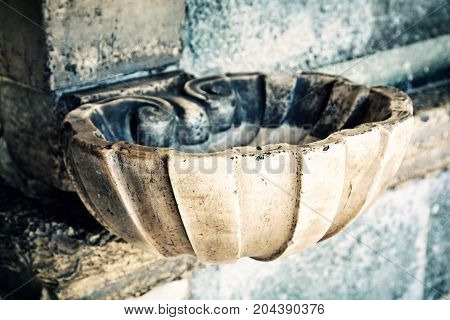 Holy water font. Religious symbol. Old photo filter.