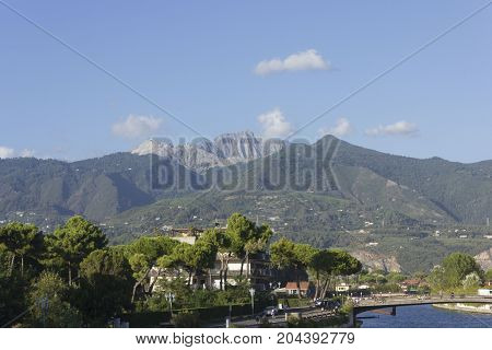 MARINA DI MASSA, ITALY - AUGUST 25 2015: View from the river front of Marina di Massa of the famous Tuscany Apuan Alps with the Carrara marble quarries
