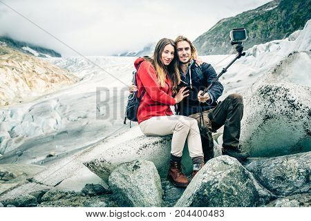 Young Couple Hiking in the Swiss Alps, Taking a Selfie. This is a generic, low-cost camera and not the 'famous original' brand.