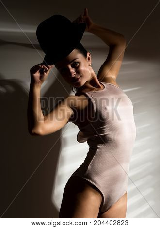 sexy woman in a beige swimsuit and black hat in a shadow stripe.