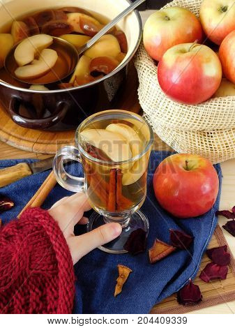 Apple compote in an Irish mug. Female hand is holding a glass of warm compote