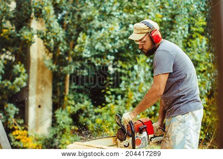 Portrait of lumberjack logger worker in protective workwear with chainsaw at forest