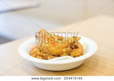Delicious crispy fried chicken wings with green cabbage for snack serve on white plate for food background or texture - homemade concept.