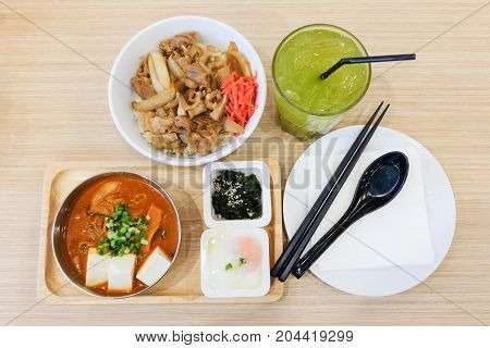 Food set consists of rice with grilled pork teriyaki spring onion & carrot on top bowl serve with tofu & cabbage soup (kimchi) soft boiled egg (onsen) wakame seaweed and green tea - japanese food.