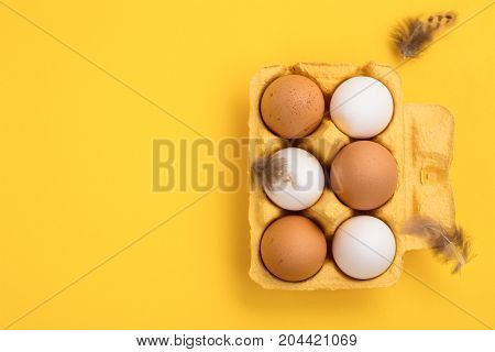 Fresh raw brown and white eggs over yellow background. Space for text