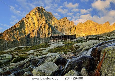 Sunrise in High Tatras in Slovakia. Monumental peak Prostredny hrot. Summer scenic landscape mountain view. Alpine trail. Small cold valley with Tery cottage.
