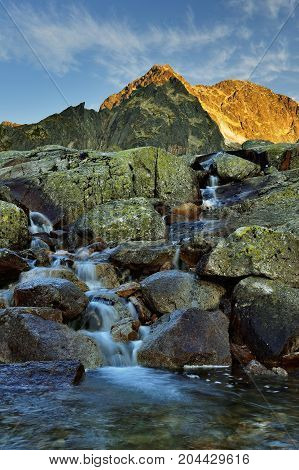 Sunrise in High Tatras in Slovakia. Monumental Ladovy peak. Summer scenic landscape mountain view. Alpine trail. Small cold valley with Small cold stream