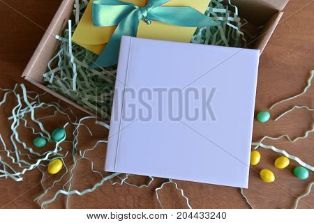 cardboard box is opened with a gift book with white color and candy and paper shavings