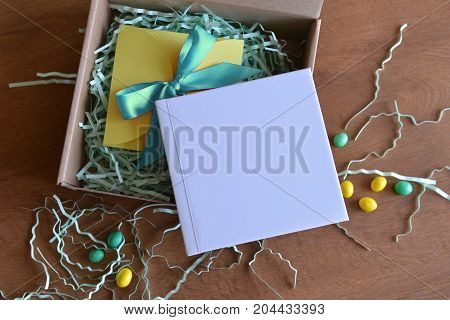 cardboard box is opened with a gift book with white color and candy and paper shavings