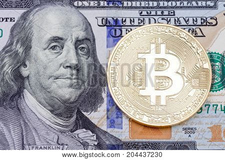 Close up of golden bitcoin on one hundred banknote. High resolution photo.