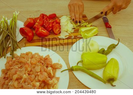 Preparing fresh meal in the kitchen. cooking food and home concept - close up of Woman hand cutting food on cutting board at home - Retro color