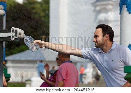 SERGIYEV POSAD/ RUSSIA - AUGUST 3, 2017. Young man pouring the holy water in a bottle from the Holy spring at the Sergiyev Posad monastery. Moscow region, Russia.