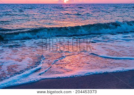 pink and blue sunlight reflecting on ocean waves at sunrie