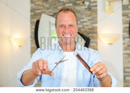 hairdresser showing comb and scissors in her shop
