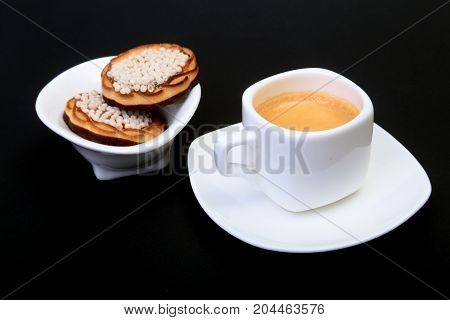 Classic espresso in white cup with homemade cake on black background. Selective focus