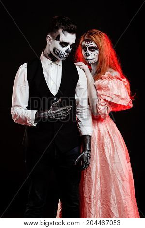 A classy couple, wearing skull make-up for. All souls day. Boy and girl in costumes of skeletons and sugar skull makeup
